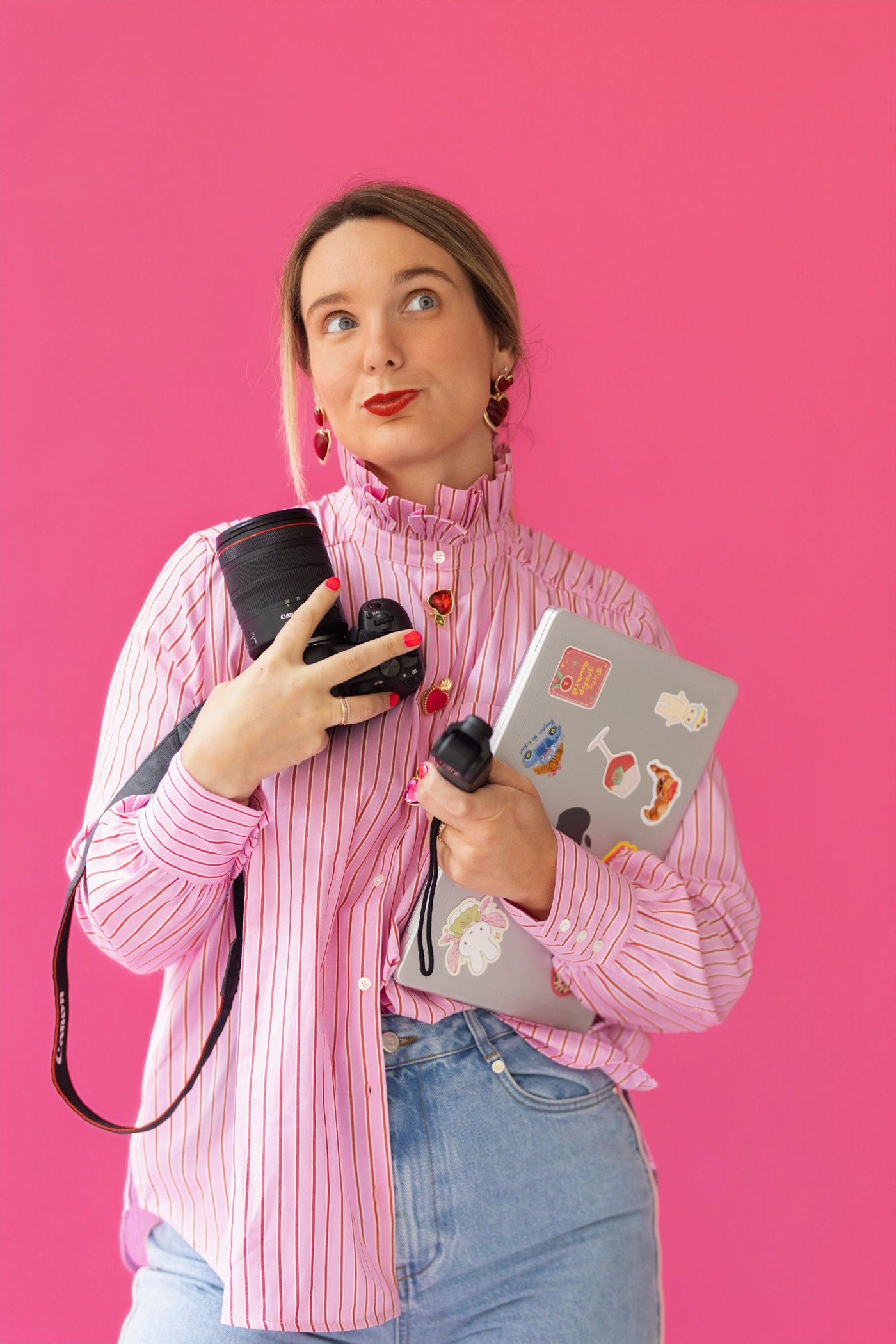 Marie Cotrel sur fond rose, appareil photo, caméra et ordinateur à la main