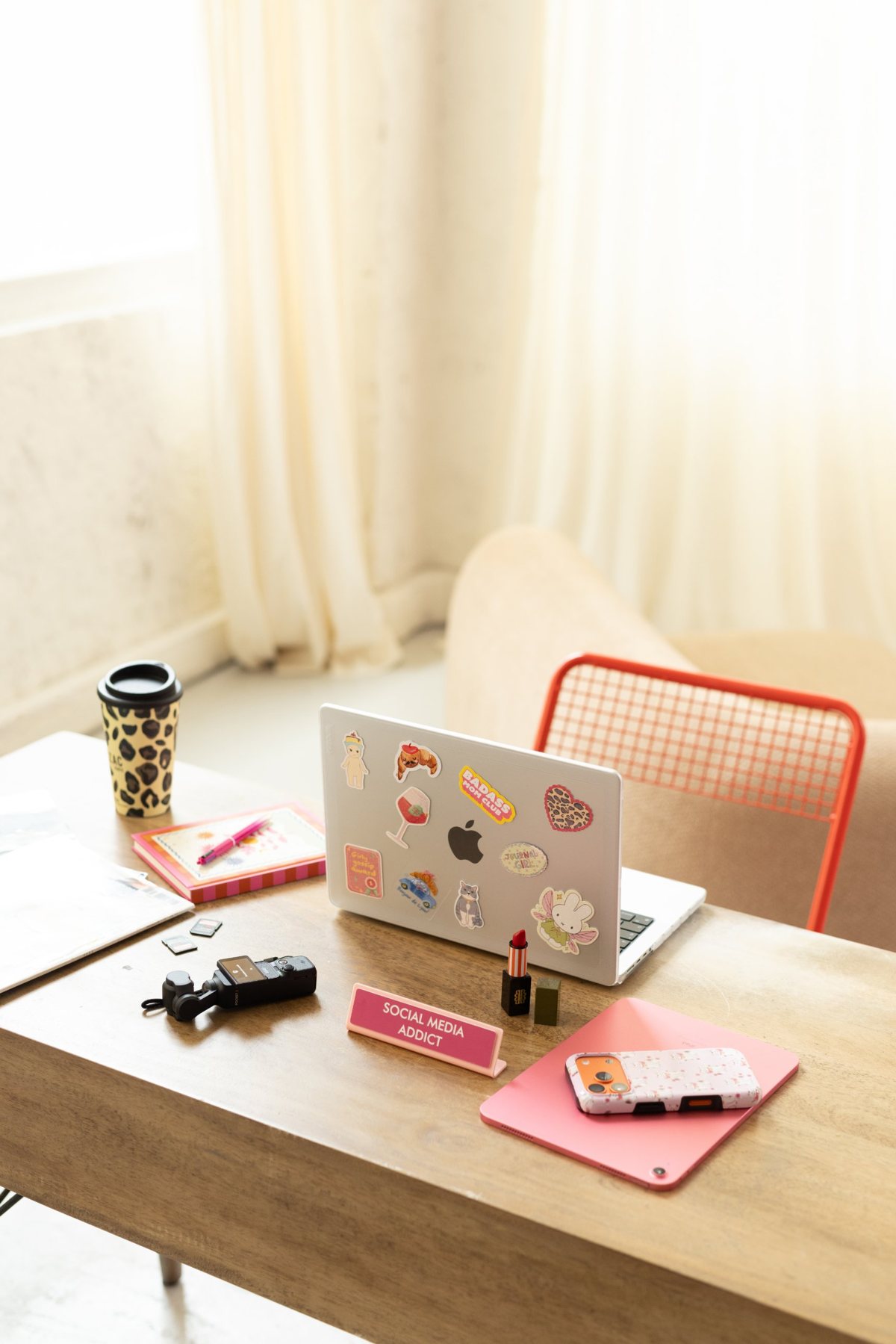 Le bureau du studio : ordinateur couvert d'autocollants, café, appareil vidéo et plaque « Social Media Addict »