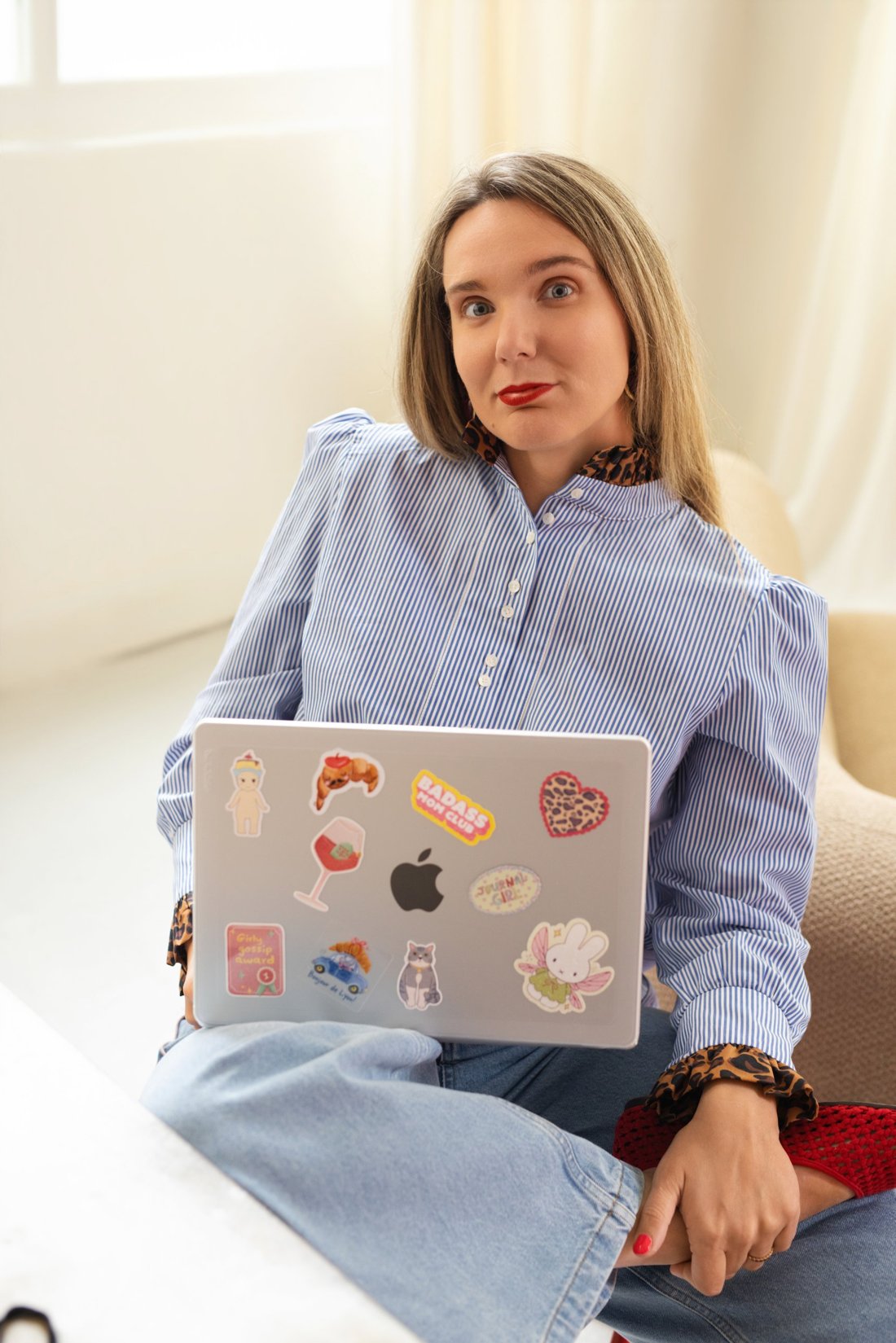 Marie Cotrel en chemise rayée, ordinateur portable couvert d'autocollants sur les genoux